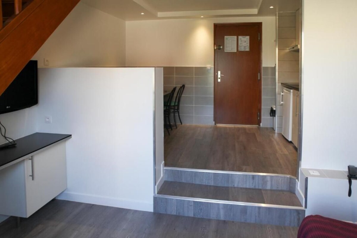 A modern kitchen with a wooden staircase leading to a dining area.