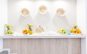 A reception area with a white counter, three woven baskets, and various fruits and bottles. - BLUESEA Cala Millor (Sant Llorenc des Cardassar)