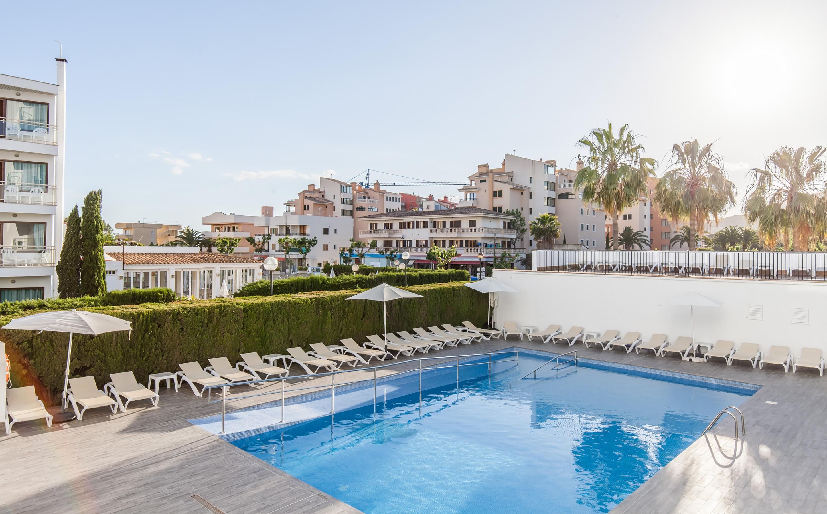 A rooftop swimming pool with lounge chairs and a view of residential buildings.