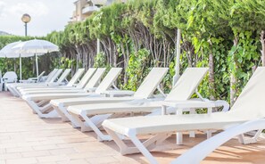 Una piscina al aire libre, sombrillas, sillones reclinables de piscina