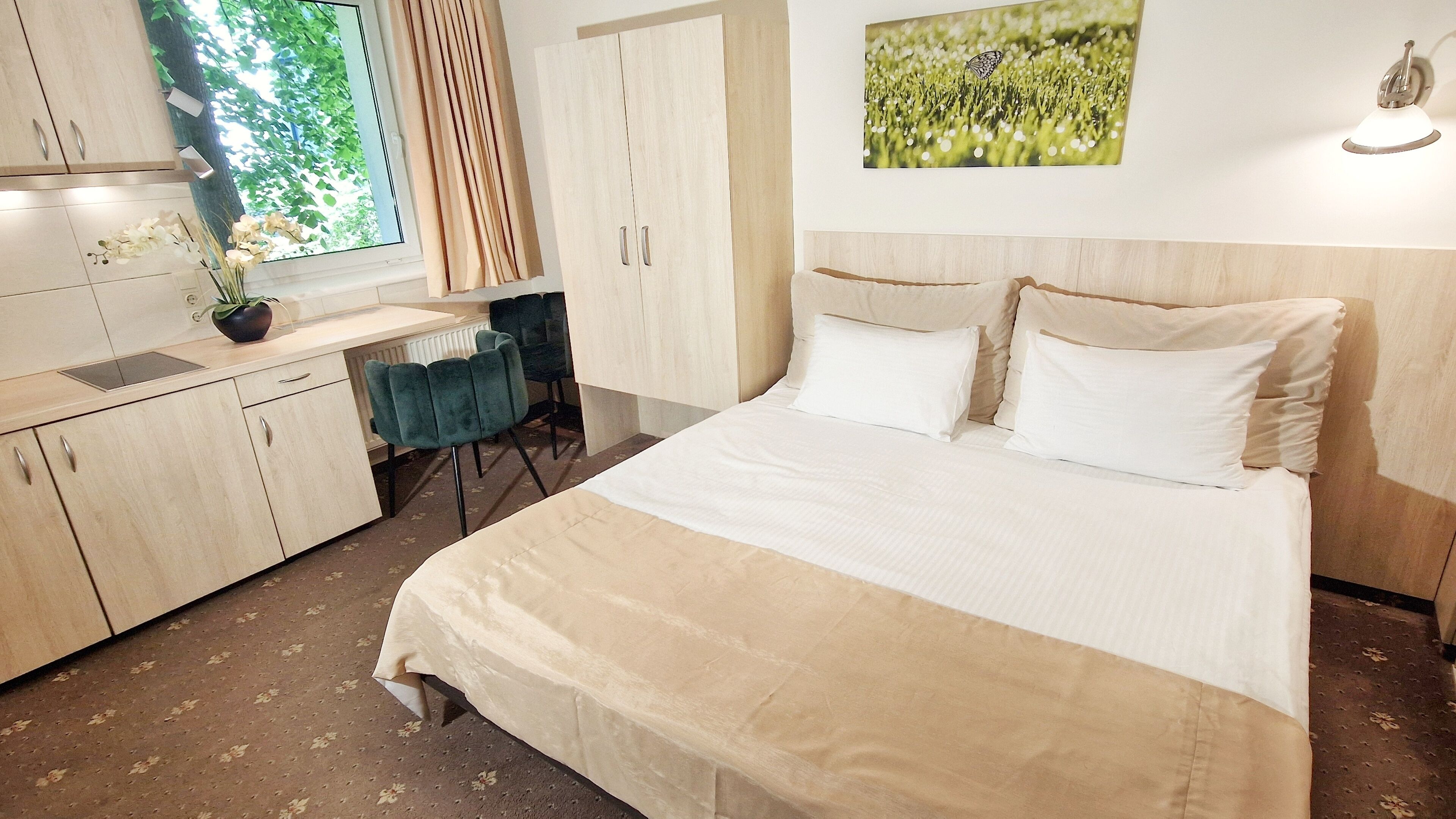 A bedroom with a bed, a desk, and a chair. There is a window with curtains, a radiator, and a plant on the desk.