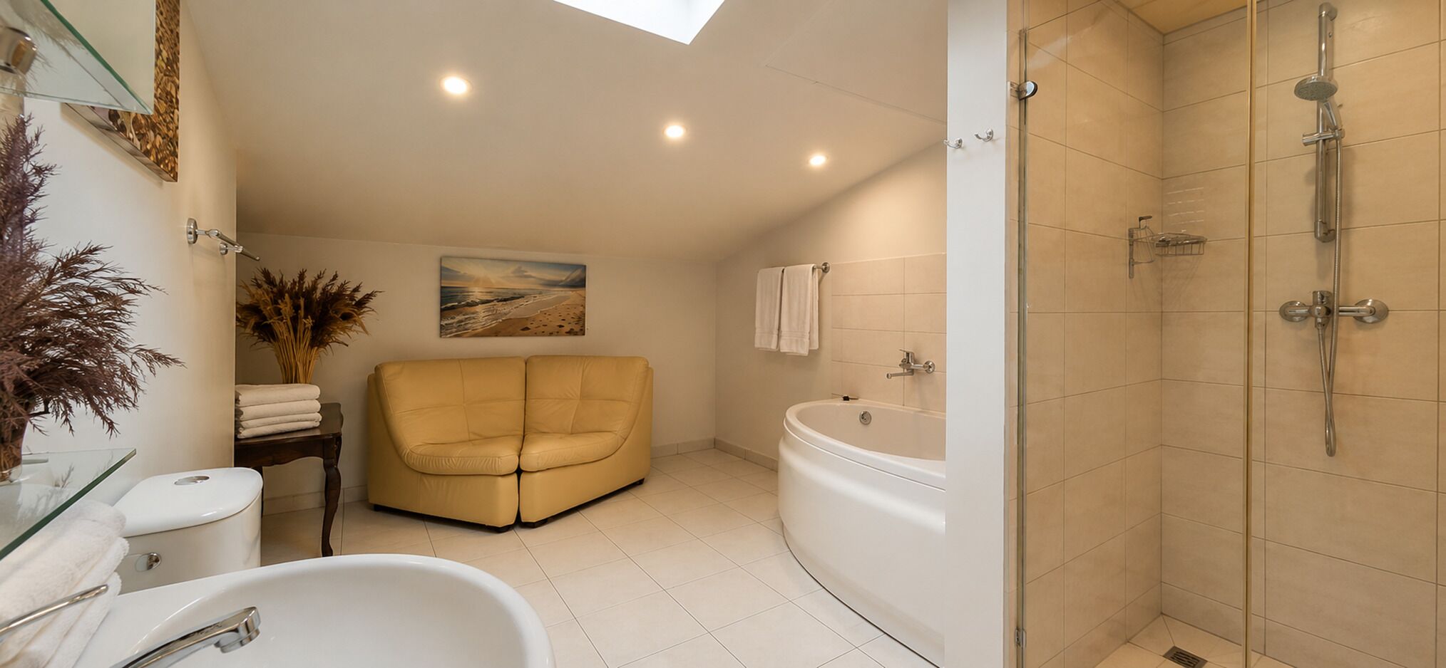 A modern bathroom with a bathtub, shower, and a beige sofa.
