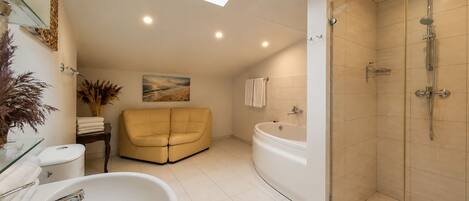 Un baño moderno con bañera, ducha y un sofá color beige.