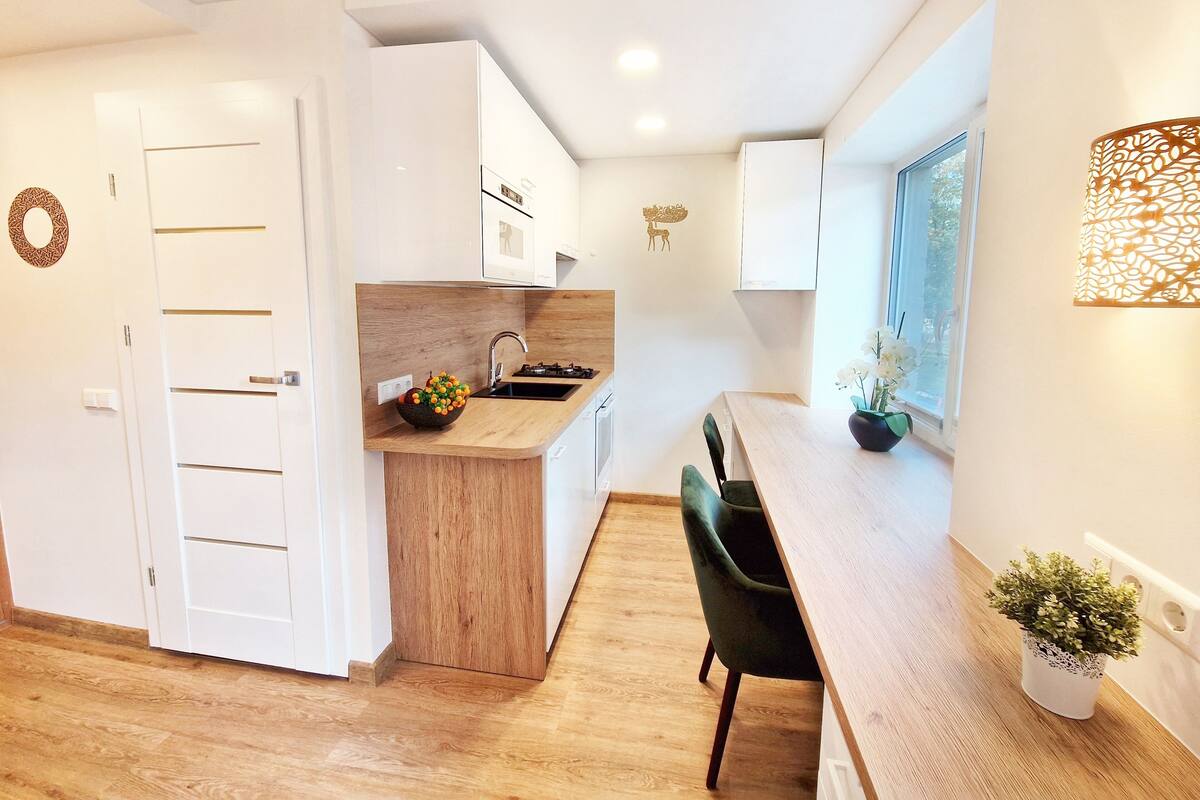 Una cocina moderna con encimera de madera, un lavamanos y una estufa. Hay un comedor con una mesa y sillas.