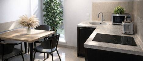 A modern kitchen with a dining area, featuring a wooden table, black chairs, a sink, a microwave, and a toaster.