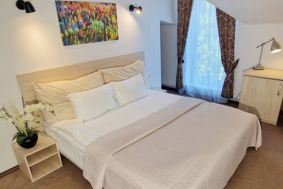 Un dormitorio con una cama grande, una mesita de noche con lámpara, un escritorio y una silla.