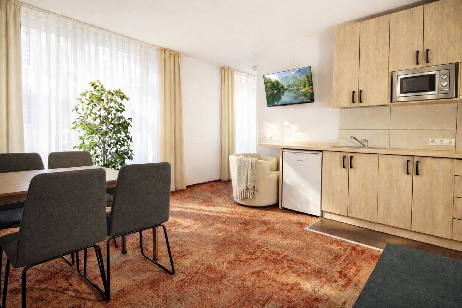 Eine moderne Küche mit Holzschränken, einer eingebauten Mikrowelle und einem kleinen Kühlschrank.