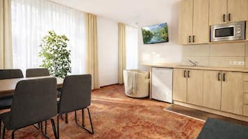 Eine moderne Küche mit Holzschränken, einer eingebauten Mikrowelle und einem kleinen Kühlschrank.