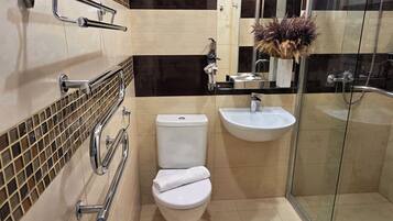 A modern bathroom with a toilet, sink, and glass shower enclosure.