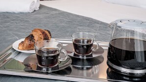 A hotel room with a bed, a tray with a croissant, a cup of coffee, and a coffee pot. - HOME Apart-Hotel Vilnius (Vilnius)