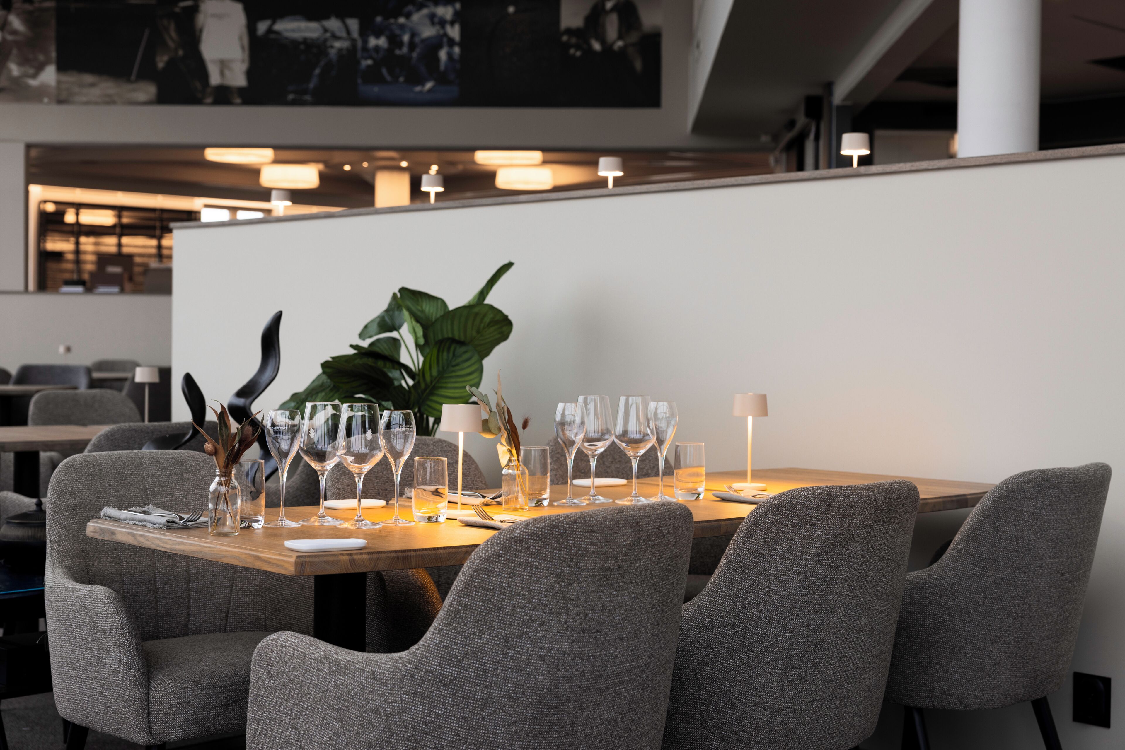 Uma sala de jantar com uma mesa comprida posta para refeição, cercada por cadeiras estofadas.