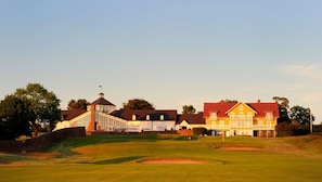Un campo de golf con un club de campo y un edificio amarillo grande con techo rojo.