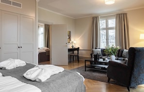 Una habitación de hotel con cama, escritorio, silla, sofá y ventana con cortinas.