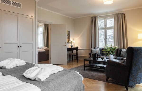 A hotel room with a bed, a desk, a chair, a sofa, and a window with curtains. - Ekerum Resort Öland (Borgholm)
