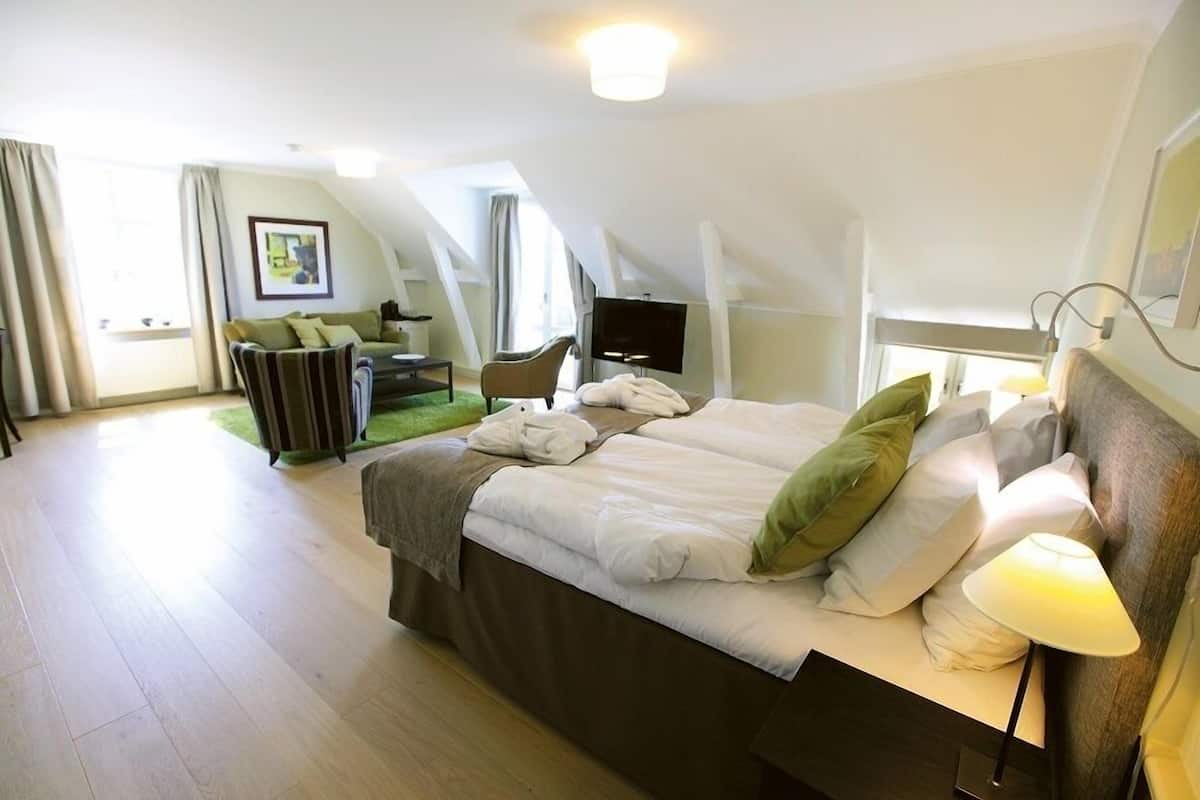 Ein modernes Hotelzimmer mit einem großen Bett, einem Flachbildfernseher und einer Sitzecke.