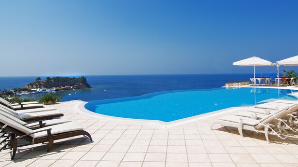 A poolside area with lounge chairs and umbrellas, overlooking a clear blue sea and a distant island. - LaVista Boutique Hotel & Spa - Boutique Class (Kusadasi)
