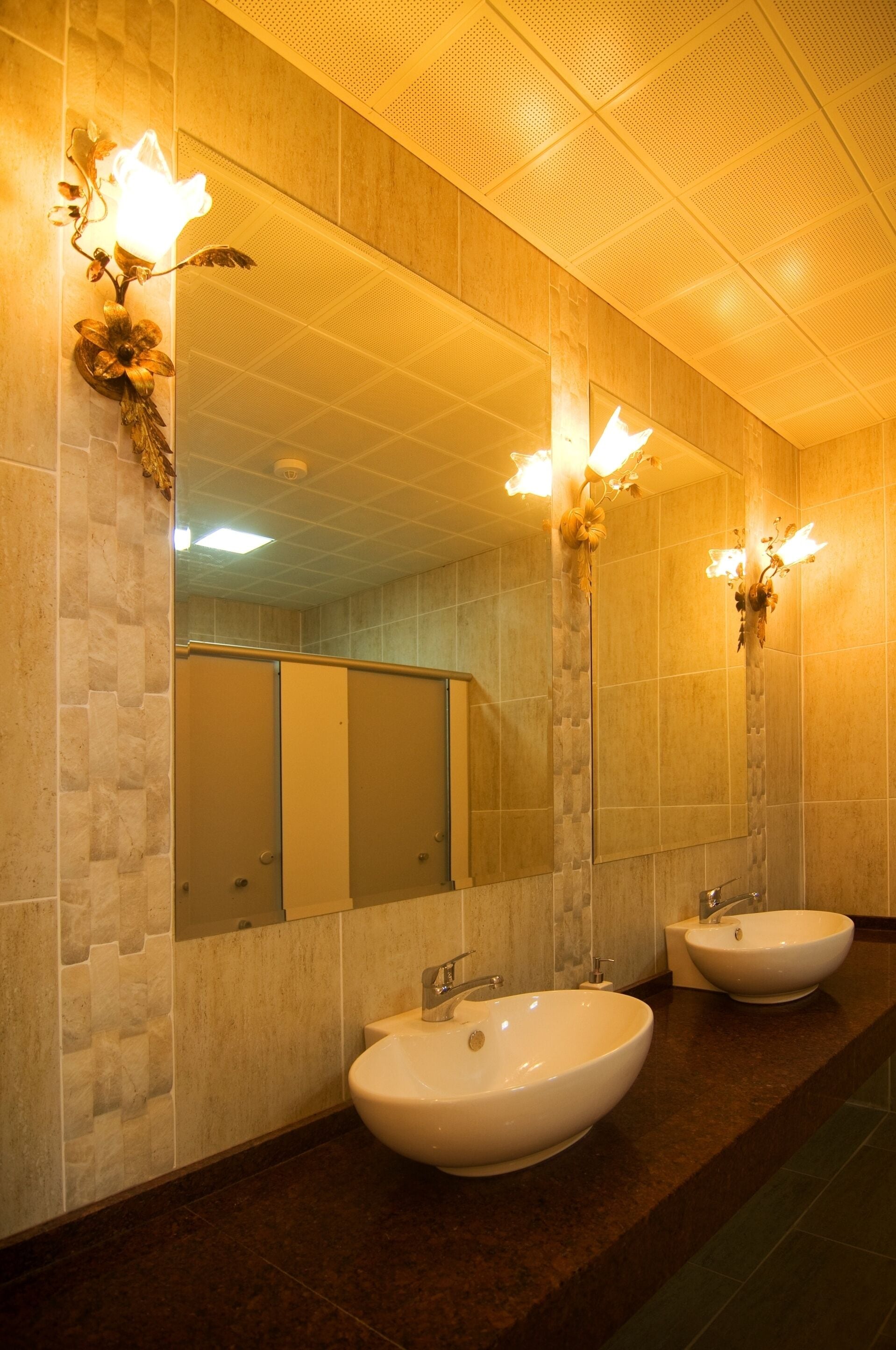 A bathroom with two sinks, a large mirror, and wall sconces.