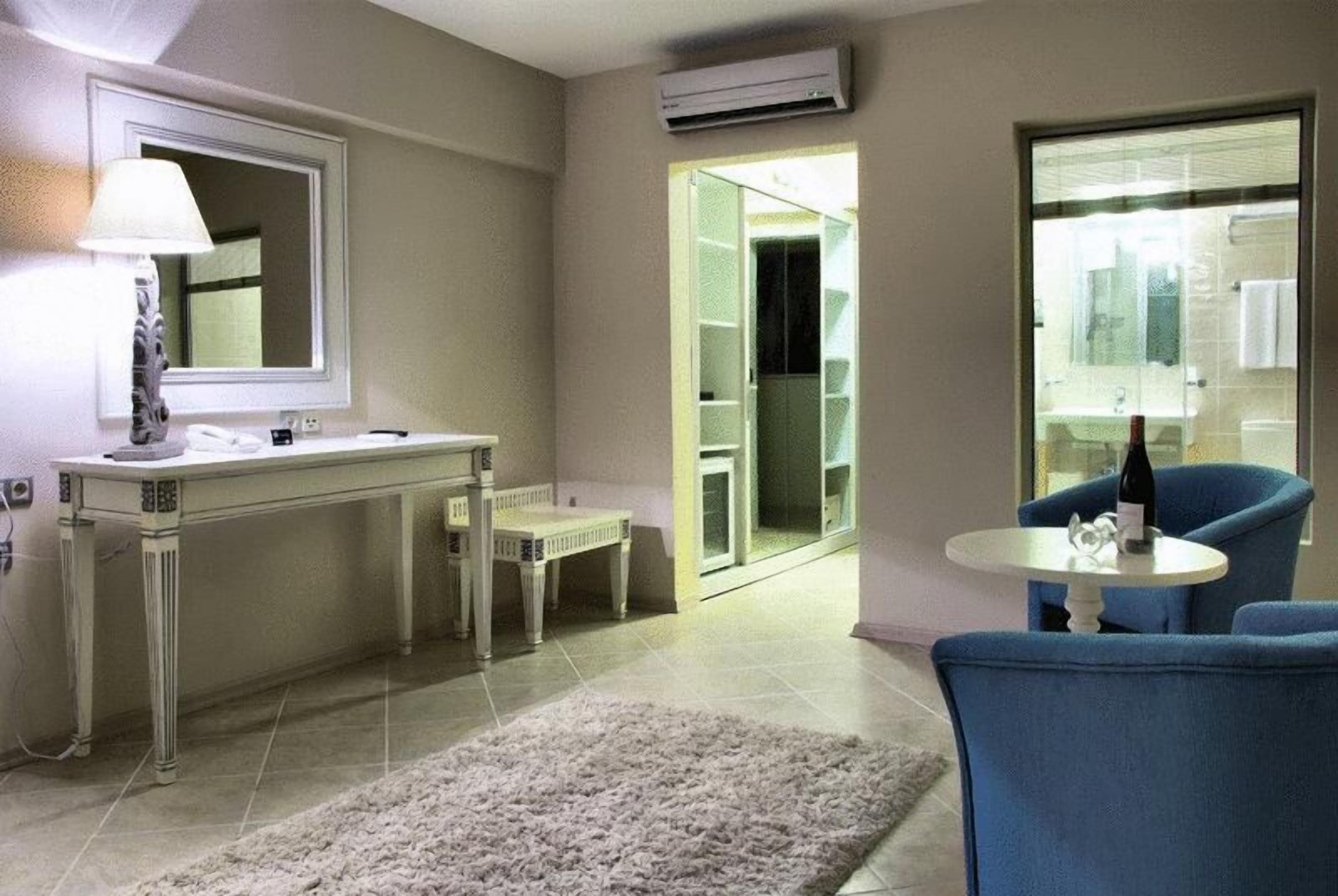 A modern bathroom with a vanity, mirror, and a small seating area with a table and chairs.