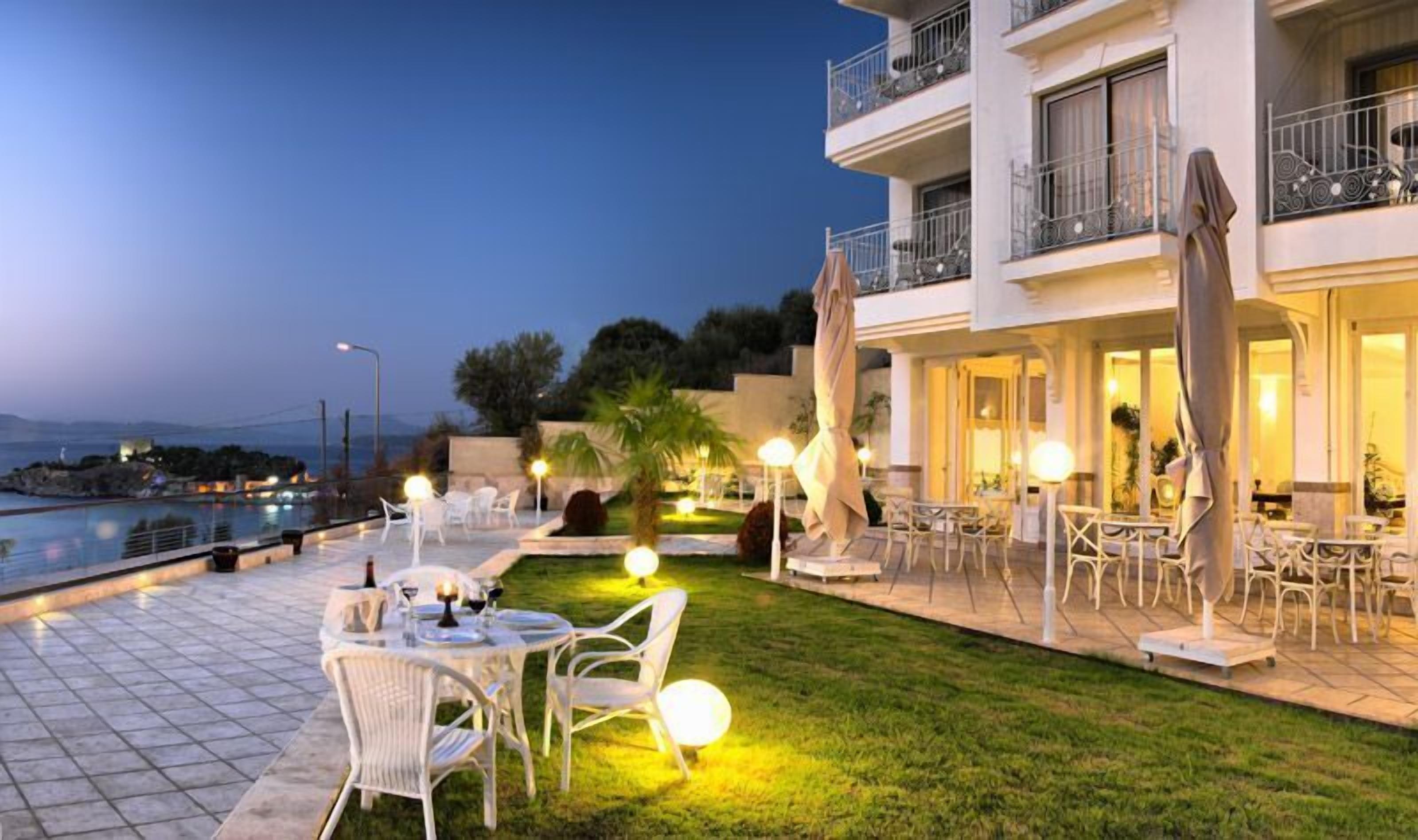 An outdoor dining area with tables and chairs, a pool, and a building with balconies.