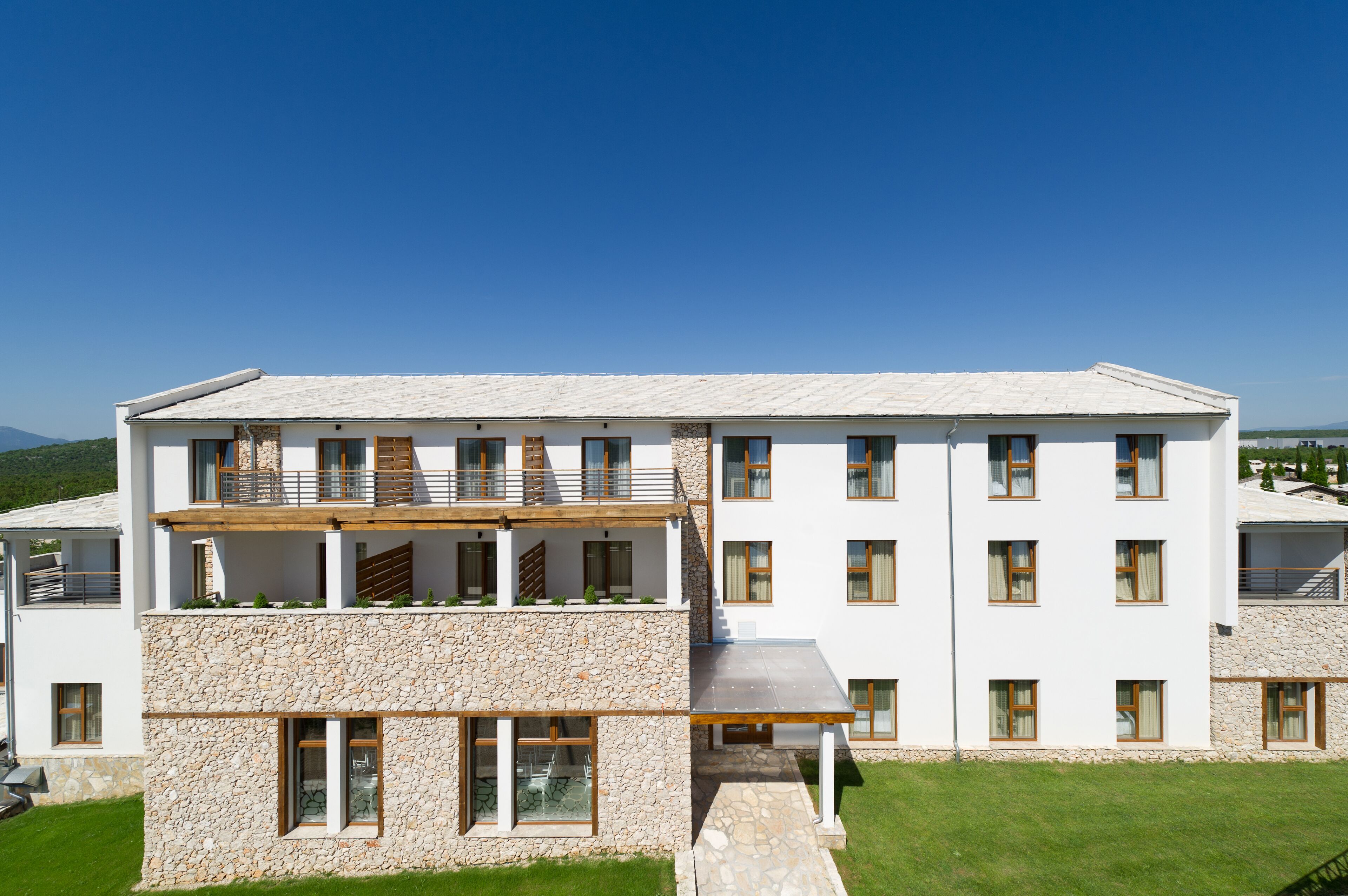 A multi-story building with a stone facade, multiple balconies, and a flat roof.