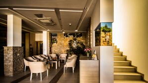 A modern interior with a stone wall, a staircase, and a seating area with chairs and a table.