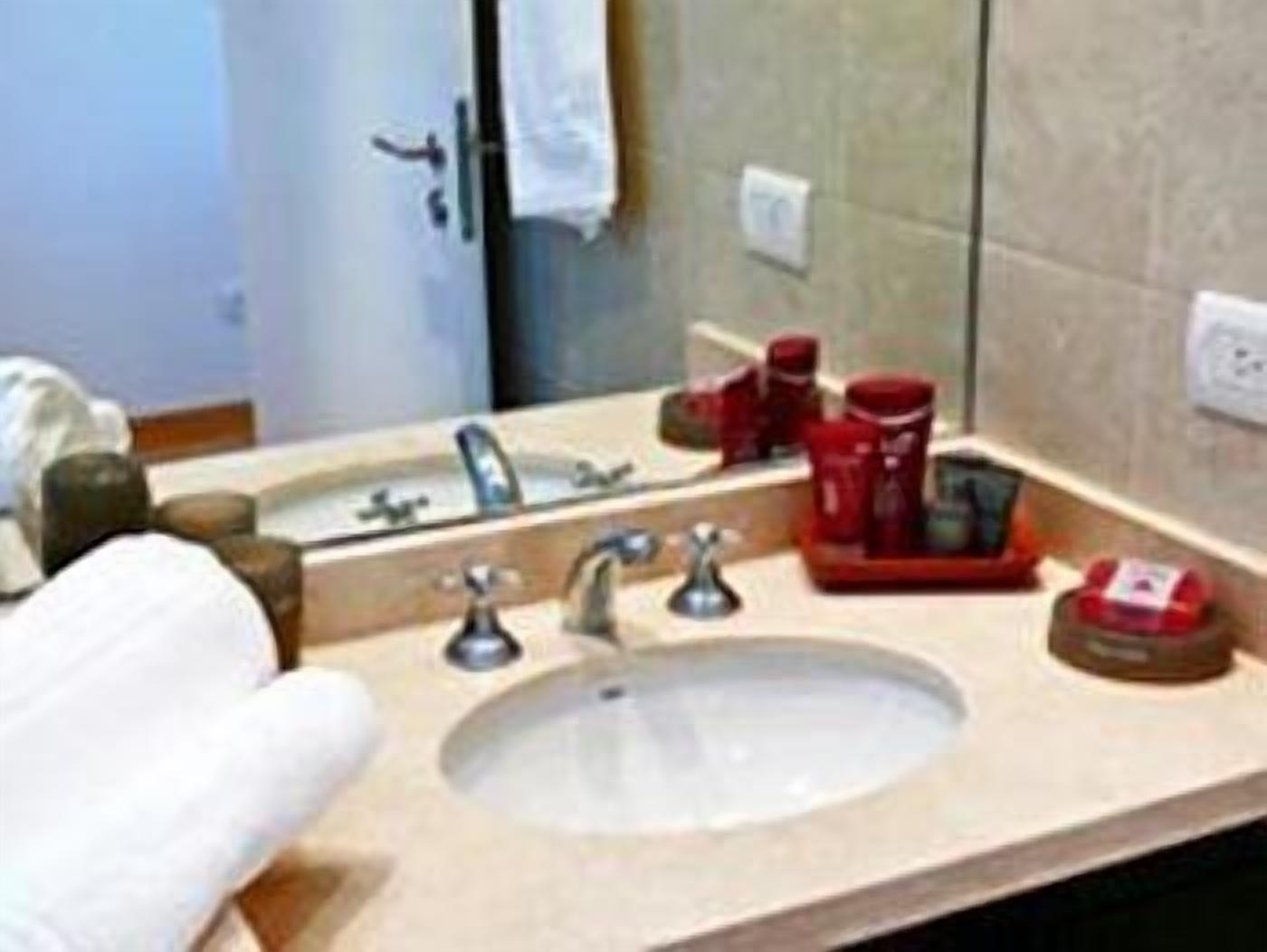 A bathroom with a sink, mirror, and toiletries.