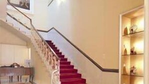 A staircase with red carpet leading to a landing.