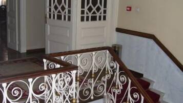 A staircase with ornate white metal railings and red carpeted steps.
