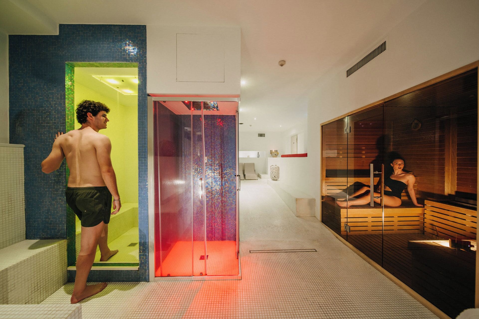 A modern spa with a glass-walled sauna, a visible shower area, and a wooden relaxation room.
