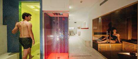 Un spa moderno con sauna de paredes de vidrio, zona de duchas a la vista y sala de relajación de madera.
