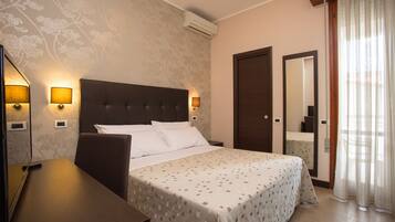 Une chambre d’hôtel équipée d’un lit, de lampes de chevet, d’un bureau, d’un miroir et d’un appareil de climatisation.