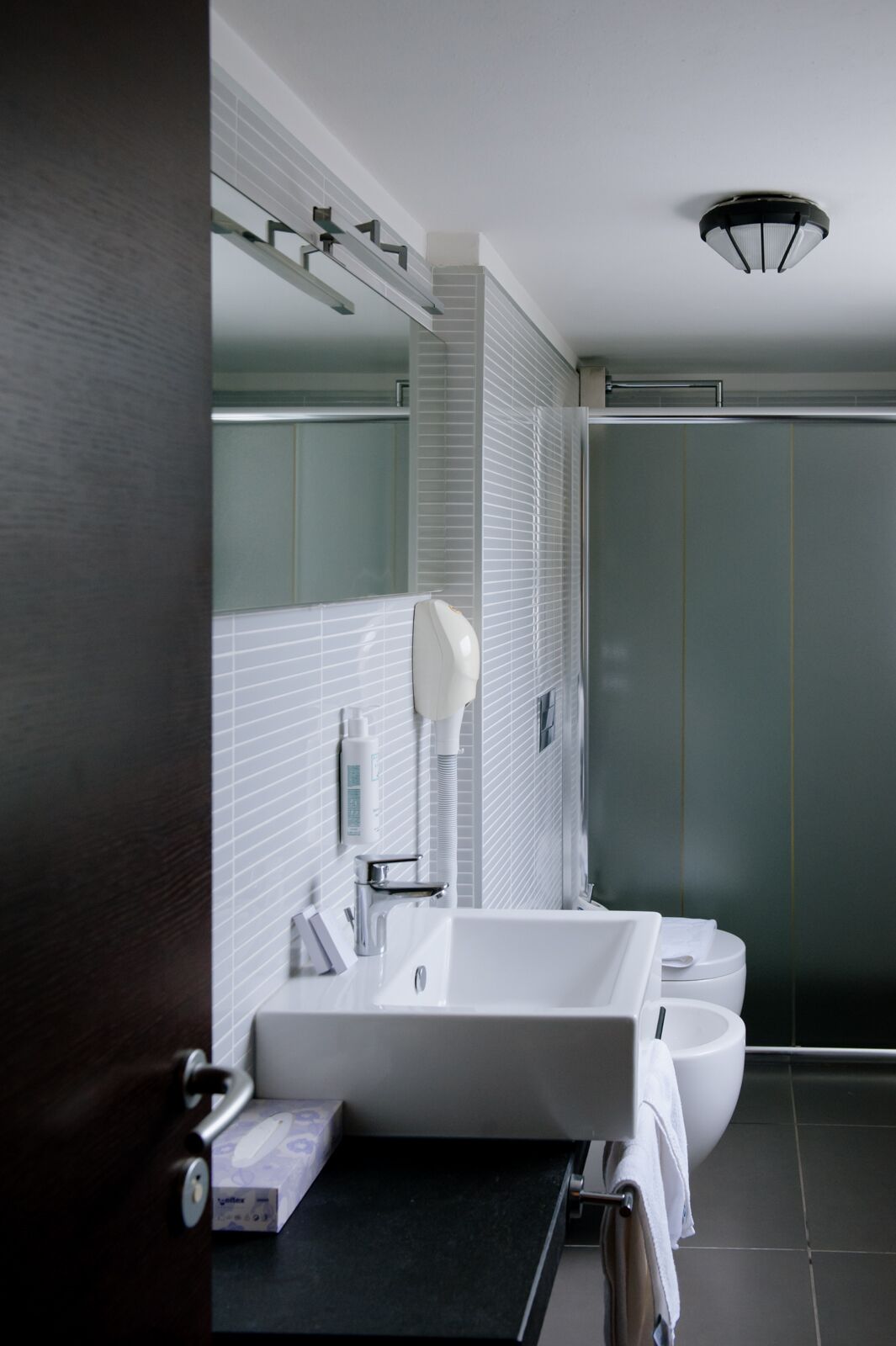 A modern bathroom with a white sink, a mirror, and a shower enclosure.
