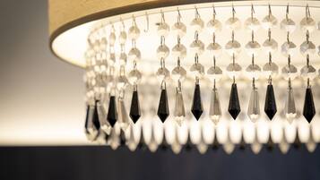 Un lampadari amb nombroses peces de cristall i una base il·luminada, davant d'una paret amb relleu.