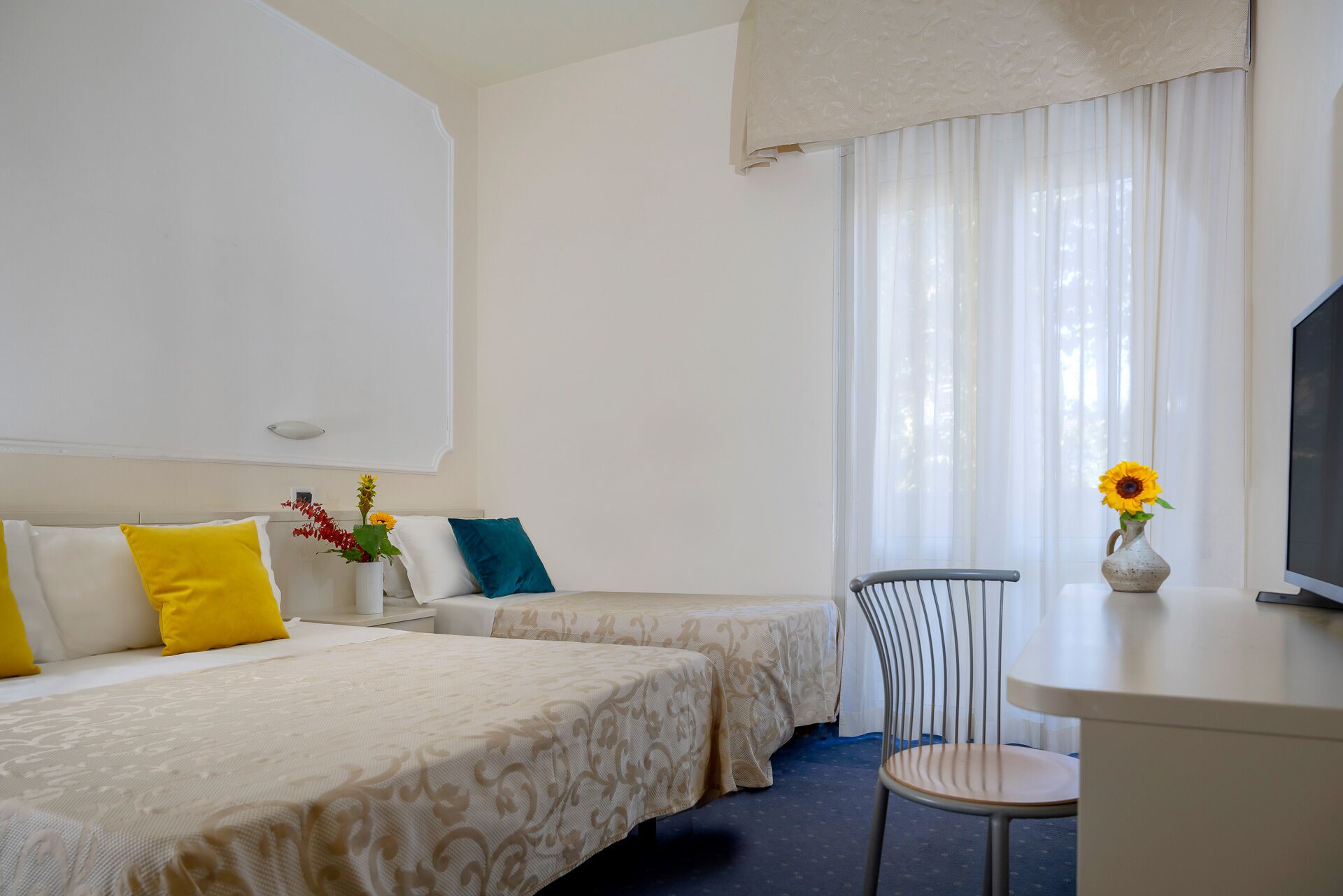 Habitación de hotel con dos camas, un escritorio, una silla y un televisor.