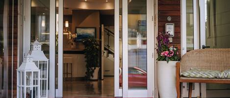 A hotel entrance with a red carpet, a wicker chair, and a white lantern.