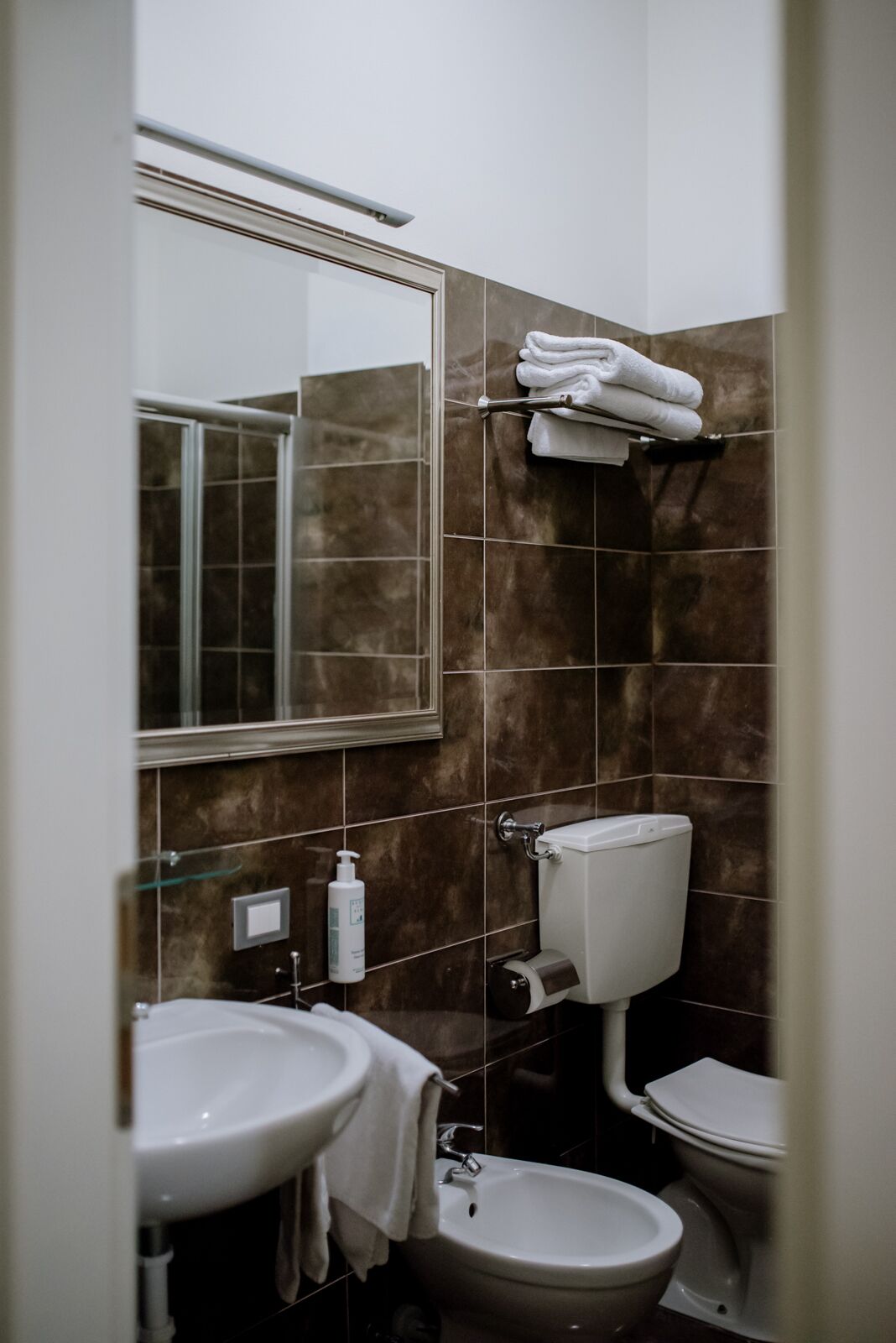Un baño con lavamanos, inodoro y espejo.