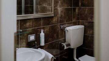Un baño con lavamanos, inodoro y espejo.