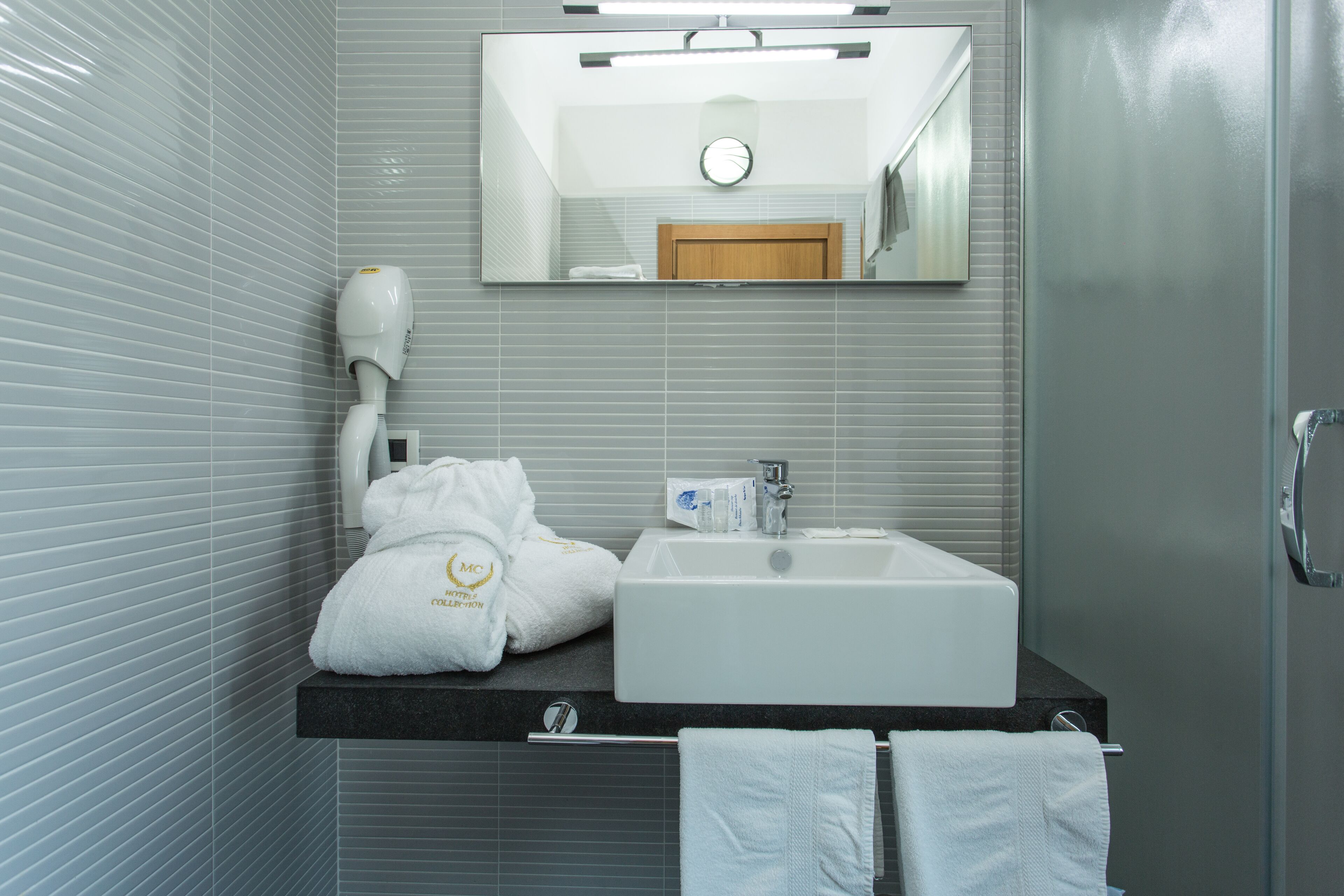 Un baño moderno con un espejo grande, un lavabo y un perchero para toallas.