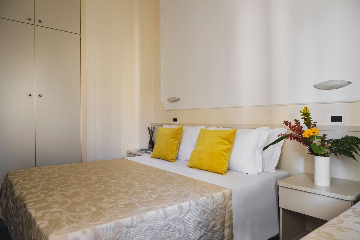 A hotel room with a bed, bedside table, and a nightstand.