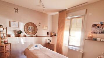 Cozy retreat with a neatly made bed, bedside table, and comfortable chair.