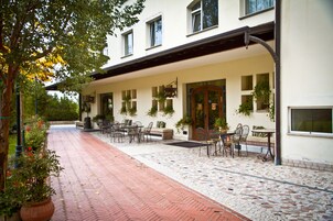 A building with a covered patio area, outdoor seating, and potted plants.