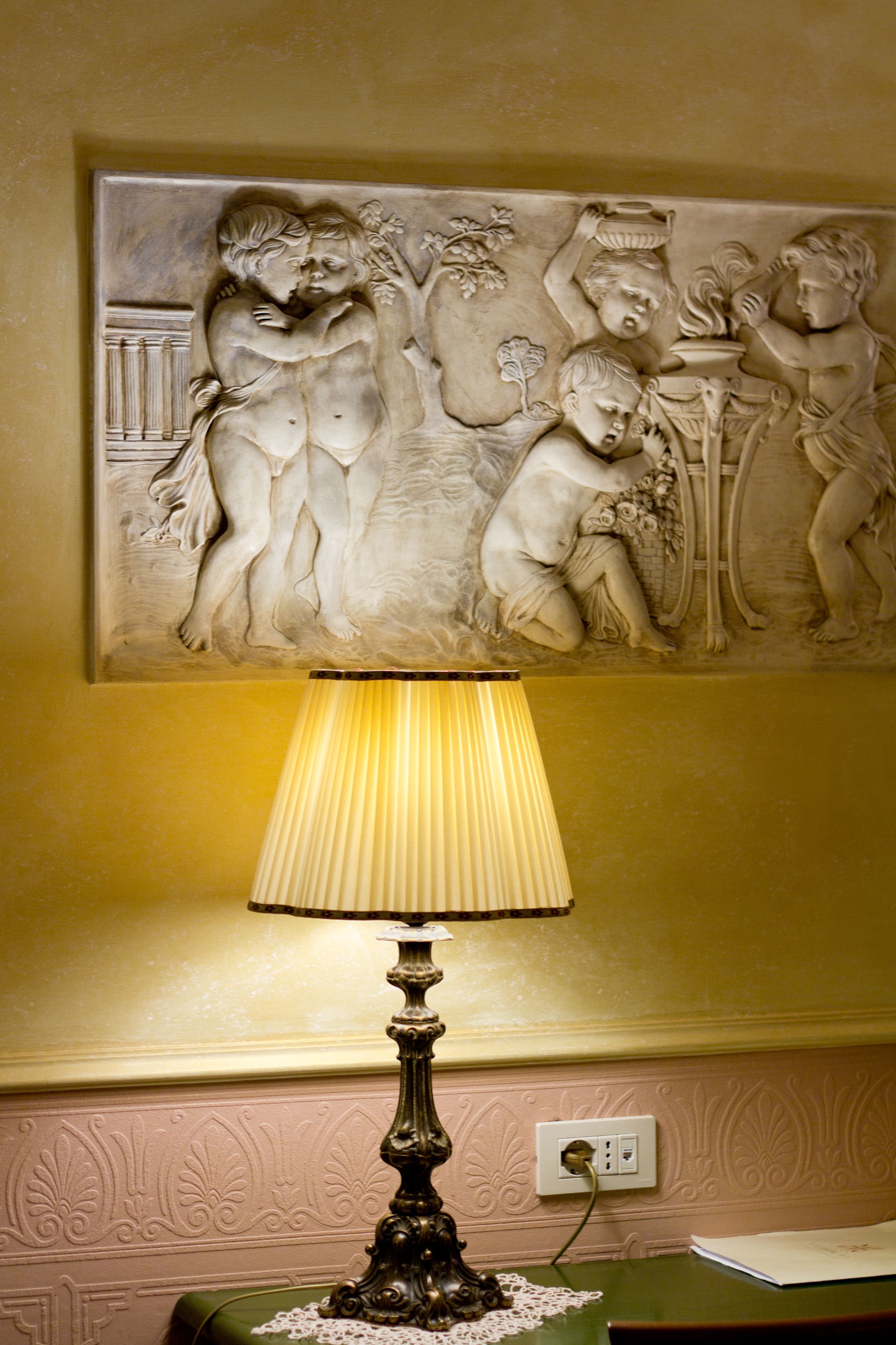 Pared con un relieve escultórico clásico y una lámpara de mesa.