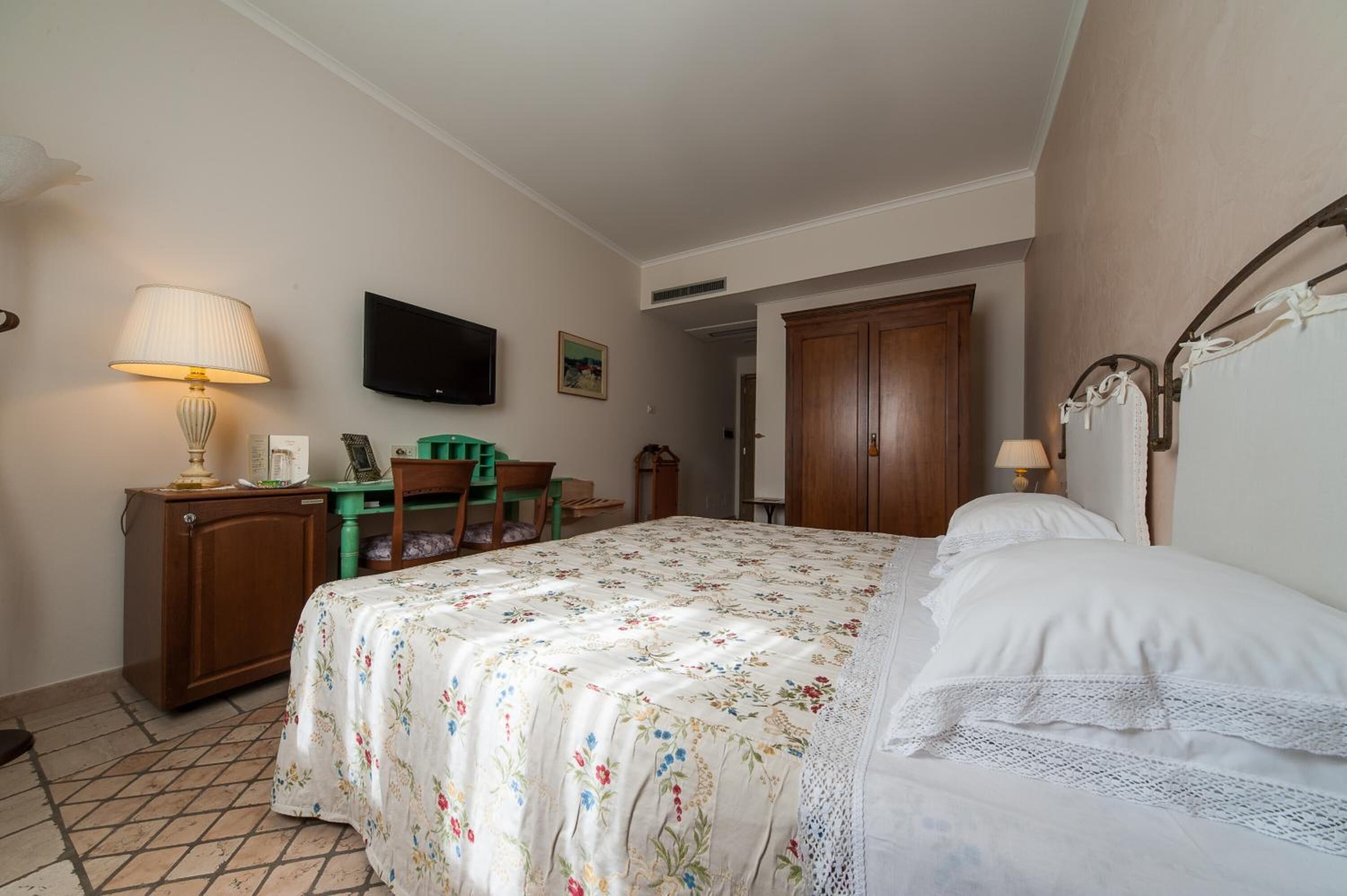 Un dormitorio con cama, escritorio, televisor y armario.