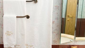 Une salle de bain avec un porte-serviettes sur lequel sont posées deux serviettes blanches, un miroir et des articles de toilette sur le comptoir.