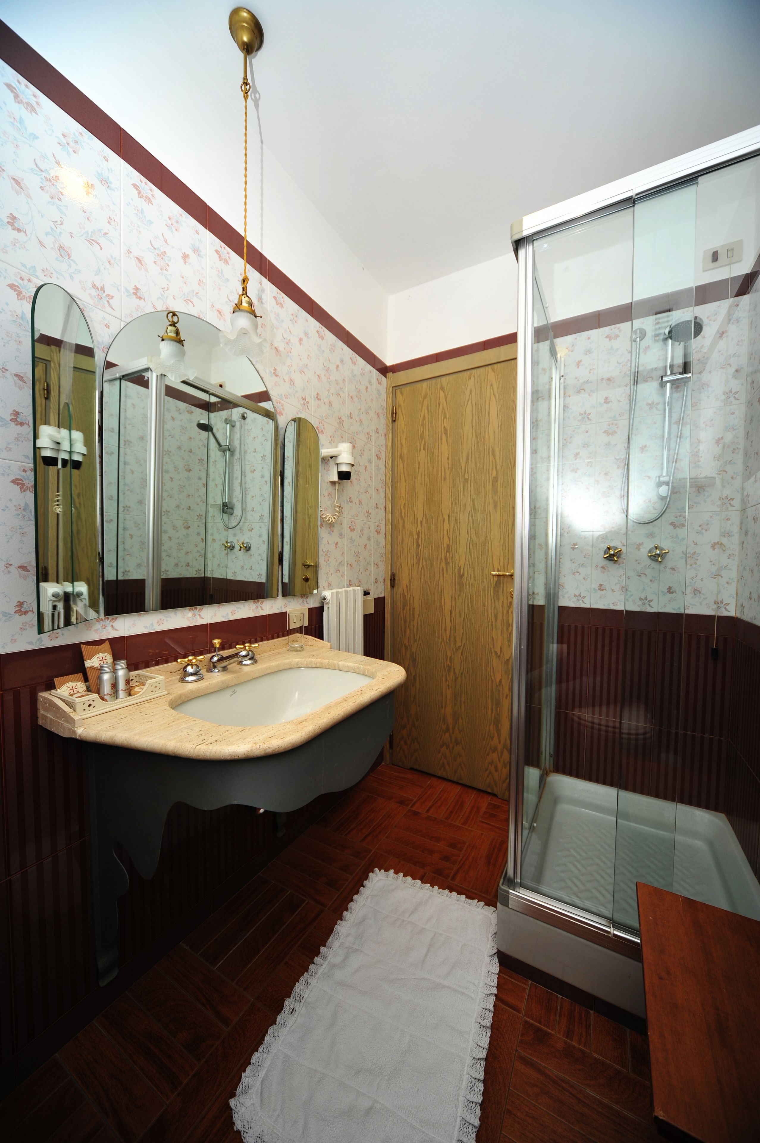 A bathroom with a large sink, a glass shower enclosure, and a wooden door.