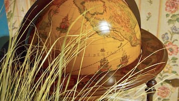 Un globe terrestre posé sur un socle en bois, avec un papier peint à motifs floraux en arrière-plan.