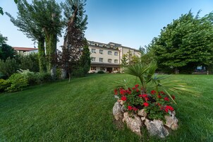 A building with a garden in front, featuring a rock planter with red flowers.
