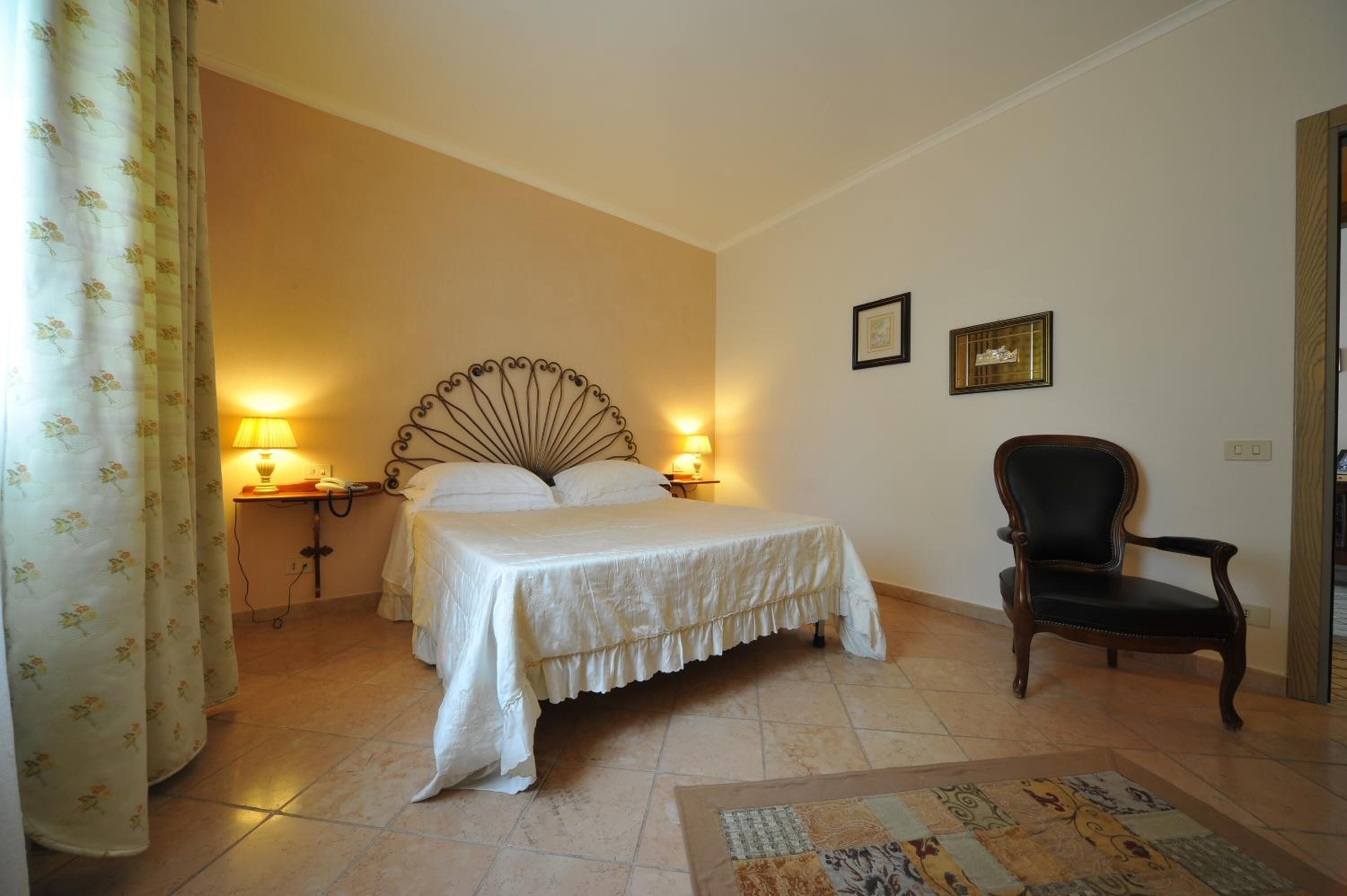 A bedroom with a bed, two bedside lamps, a chair, and a rug.