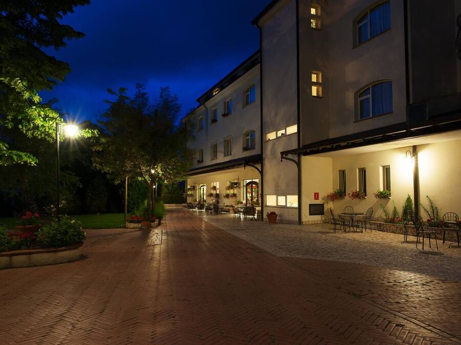 A paved courtyard with outdoor seating, a building with multiple windows, and a street lamp.