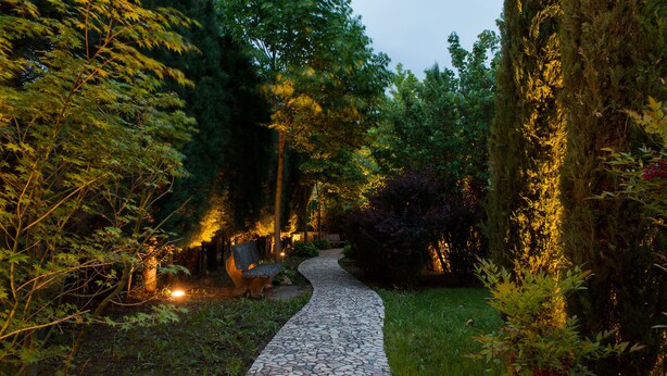 A stone pathway in a garden with benches and trees. - La Primula (Potenza)